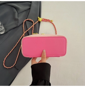 Detailed view of the bright pink small square bag with gold chain strap and neat stitching