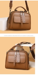 Detail view of brown faux leather handbag with dual zippers and decorative metal rivets