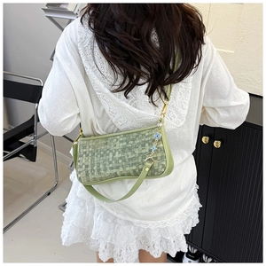 Detail of light green woven leather shoulder bag with floral metal charm accessory
