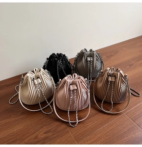 Top view of pleated drawstring bucket bags in five colors on a wooden floor