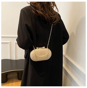 Detail of champagne gold sequin clutch bag with metallic bow clasp and fine chain strap