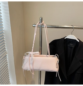 Detail view of pink rectangular shoulder bag with elegant white lace bow decoration