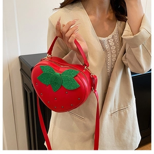 Détail du sac à main fraise rouge avec feuilles vertes pailletées et clous métal
