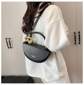 Detailed view of black semi-circular bag with gold ring buckle and shoulder strap