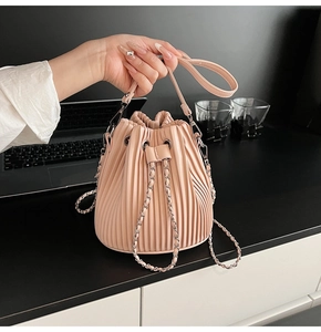 Detail of pink pleated bucket bag with silver chain strap and drawstring closure