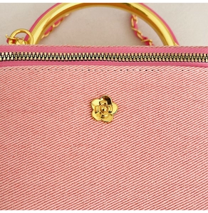 Detail of pink twill fabric texture and golden flower ornament on elegant box bag