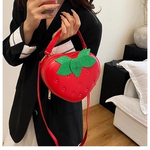 Détail du sac fraise rouge avec des rivets métalliques et des feuilles à paillettes