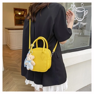 Detail of yellow pebbled leather mini square bag with cute teddy bear charm and chain strap
