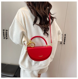 Detail of red semicircular leather box bag with large gold ring hardware and shoulder strap