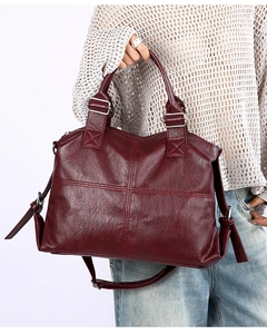 Detail of burgundy pebbled leather handbag with cross stitching and silver hardware
