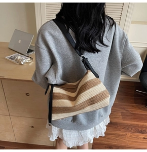 Detail of striped woven shoulder bag with adjustable black leather strap on a model