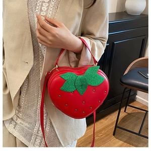 Gros plan d'un sac bandoulière fraise rouge avec des feuilles à paillettes et rivets