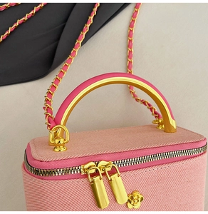Pink twill fabric crossbody bag with gold metal handle and floral charm pendant