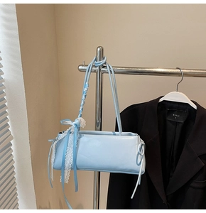 Detail of light blue baguette bag featuring delicate white lace trim and ribbon bow
