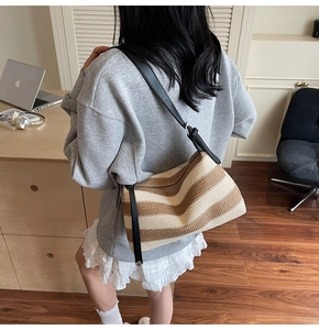 Detail of woven striped tote bag featuring brown and beige texture with a black leather strap