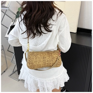 Detailed close-up of brown woven texture shoulder bag with gold hardware and flower charm
