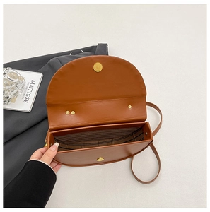 Internal view of a brown saddle box bag showing striped lining and magnetic closure