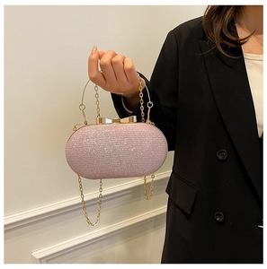 Pink rhinestone clutch bag with gold handle and chain strap shown being held by a model