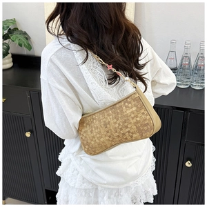 Detail of light brown woven shoulder bag featuring pink flower and pearl accents