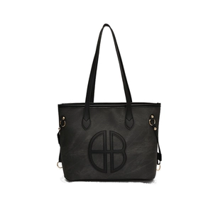 Minimalist black faux leather tote bag with round logo and golden hardware rings