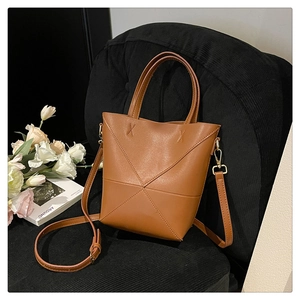 Détail du sac seau marron caramel avec coutures géométriques sur une chaise en velours