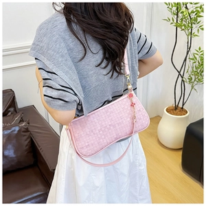 Detail of pink woven hobo bag featuring decorative beads and floral charms on strap