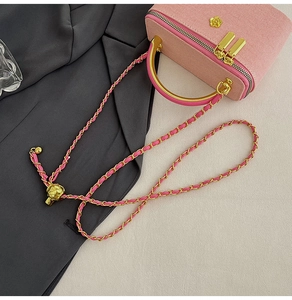 Detailed view of pink corduroy box bag with gold metal handle and woven chain strap
