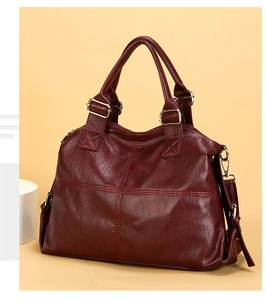 Macro shot of cross-stitch patterns and silver hardware on a burgundy leather tote bag