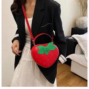 Détail du sac fraise rouge avec clous, décor de feuilles et fine bandoulière