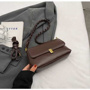 Detail of dark brown rectangle shoulder bag with woven rope strap and gold metal buckle