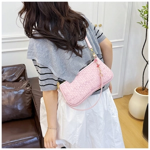 Detail of pink woven leather shoulder bag with a floral charm and intrecciato style
