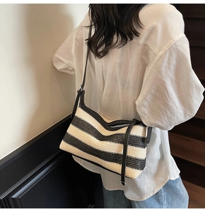 Detail of a woven black and white striped pillow bag with an adjustable leather strap