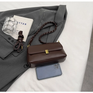 Detail of dark brown vintage shoulder bag with golden buckle on gray blazer background