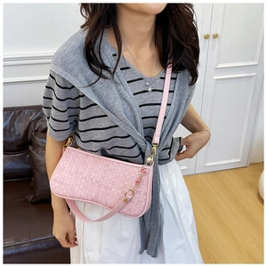 Pink woven pillow bag with floral charm shown in a cozy interior setting