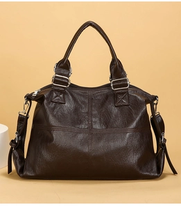 Detail view of large dark brown leather shoulder bag with vintage cross-stitch and silver zipper