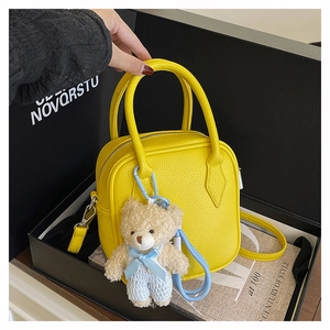 Detail of yellow pebble leather mini handbag with blue bear charm in a black gift box