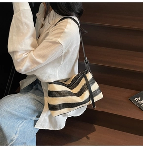 Chic black and white striped woven shoulder bag with adjustable leather strap
