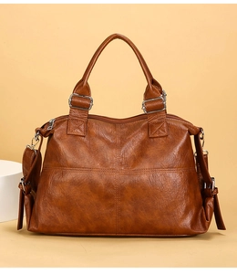 Macro shot of brown faux leather tote with cross-stitch details and silver hardware