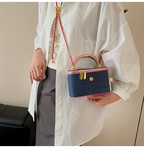 Mini crossbody bag with blue denim fabric, pink trim, and golden metal handle shown on model