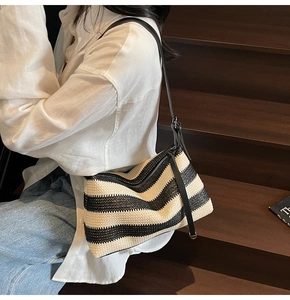 Detailed view of woven straw beach bag featuring black and white stripes and leather strap