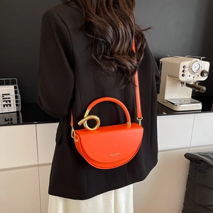 Orange half-moon crossbody box bag with gold metal twist handle and leather strap