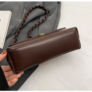 Detailed close-up of dark brown leather handbag base and unique braided shoulder strap