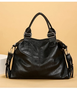 Detail of black large capacity tote bag featuring glossy soft leather and silver hardware