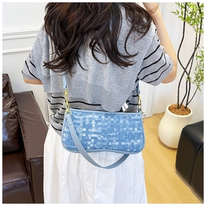 Detail of light blue checkered woven crossbody bag with golden metal hardware