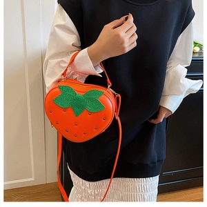 Détail du sac à bandoulière créatif en forme de fraise orange avec feuilles scintillantes