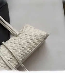 Close-up of woven cream white leather texture on stylish crossbody baguette bag