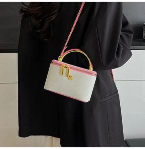 Detail of grey mini bag with pink edges, golden handle and flower charm pendant