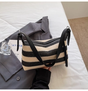 Detail of black and white striped woven underarm bag with black leather shoulder strap