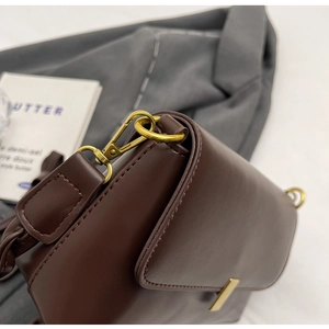 Close-up of vintage brown leather underarm bag with gold metal buckle and neat stitching