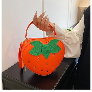 Détail du sac à main fraise en cuir orange avec feuilles scintillantes et rivets argentés
